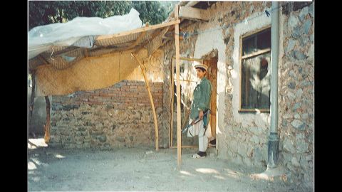 A young man stands outside the house.