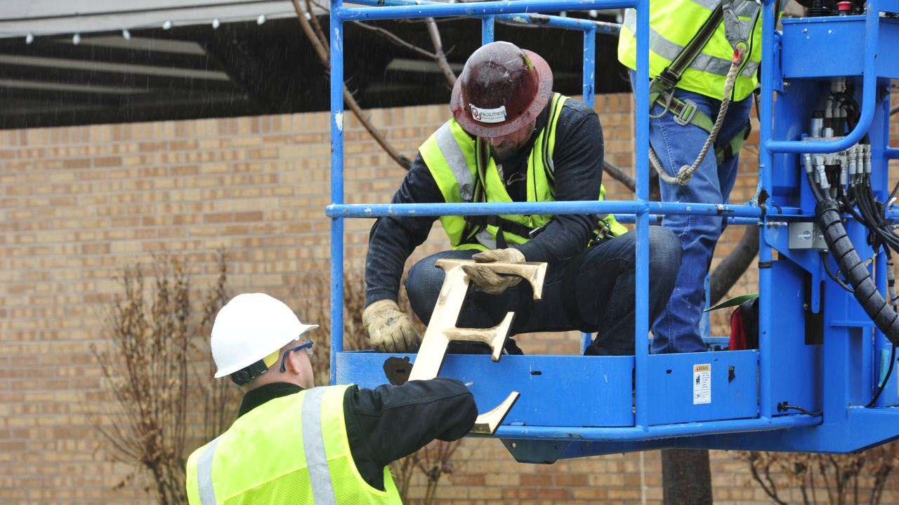 Facility workers remove the letters from the SAE house on Monday, March 9.