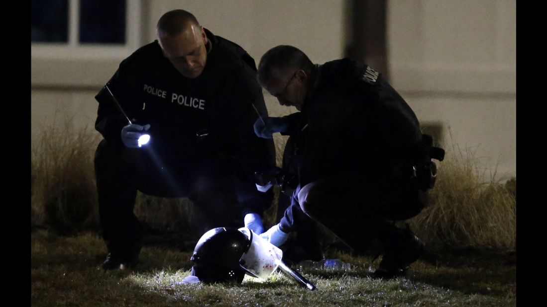 Police shine a light on a helmet as they investigate the scene outside the Ferguson Police Department on March 12.