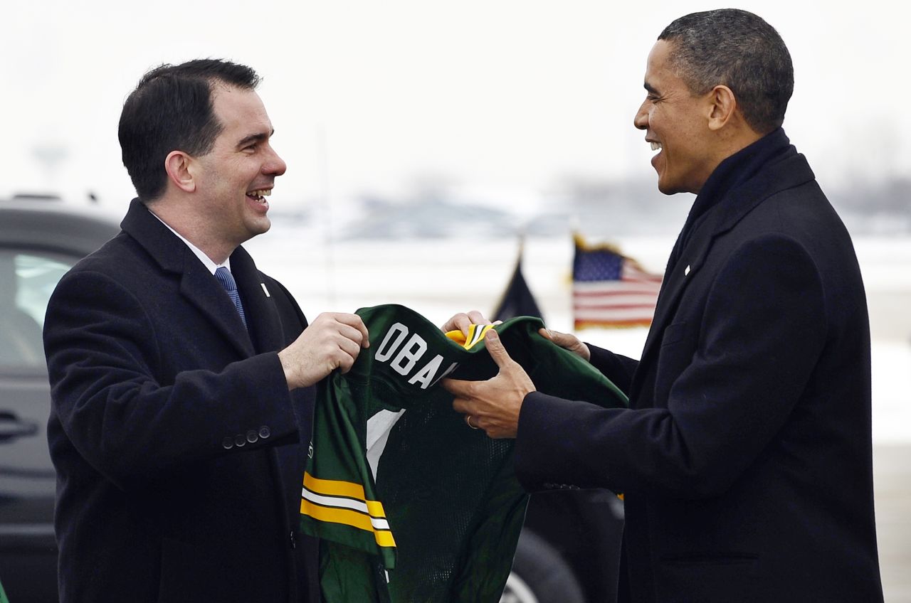 President Obama receives a Green Bay Packers NFL football team jersey with 'Obama #1' written on it from Walker (left) at Austin Straubel International Airport in Green Bay, Wisconsin, on January 26, 2011.