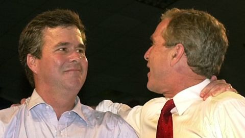 Jeb Bush (left) and then-President George W. Bush stand with their arms around each other's shoulders at a rally in Miami, Florida, September 22, 2000.