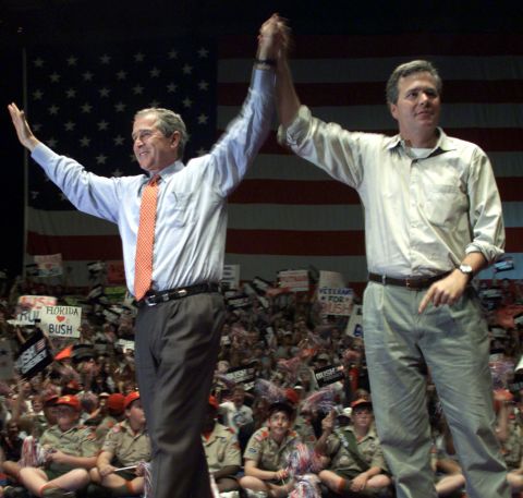 Then-President George W. Bush (left) and Jeb Bush (right), raise their arms onstage following a rally at the Florida State Fairgrounds, October 25, 2000, in Brandon, Florida. 