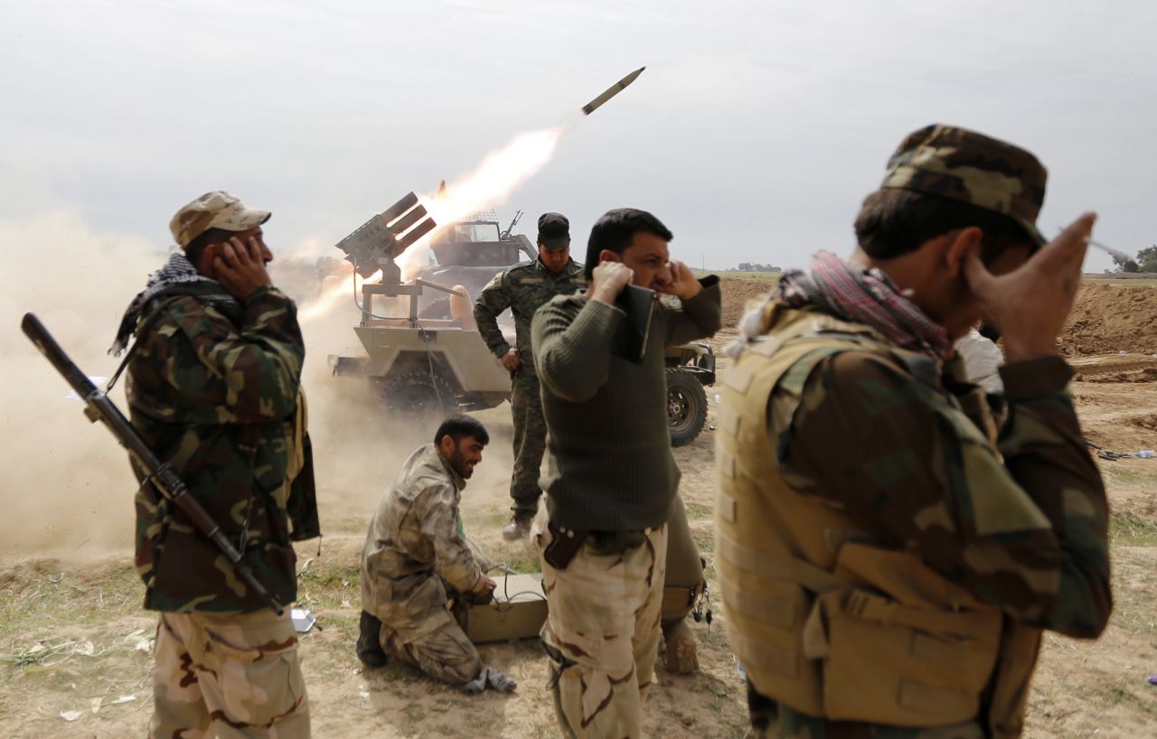 Iraqi Shiite fighters cover their ears as a rocket is launched during a clash with ISIS militants in the town of Al-Alam, Iraq, on Monday, March 9.