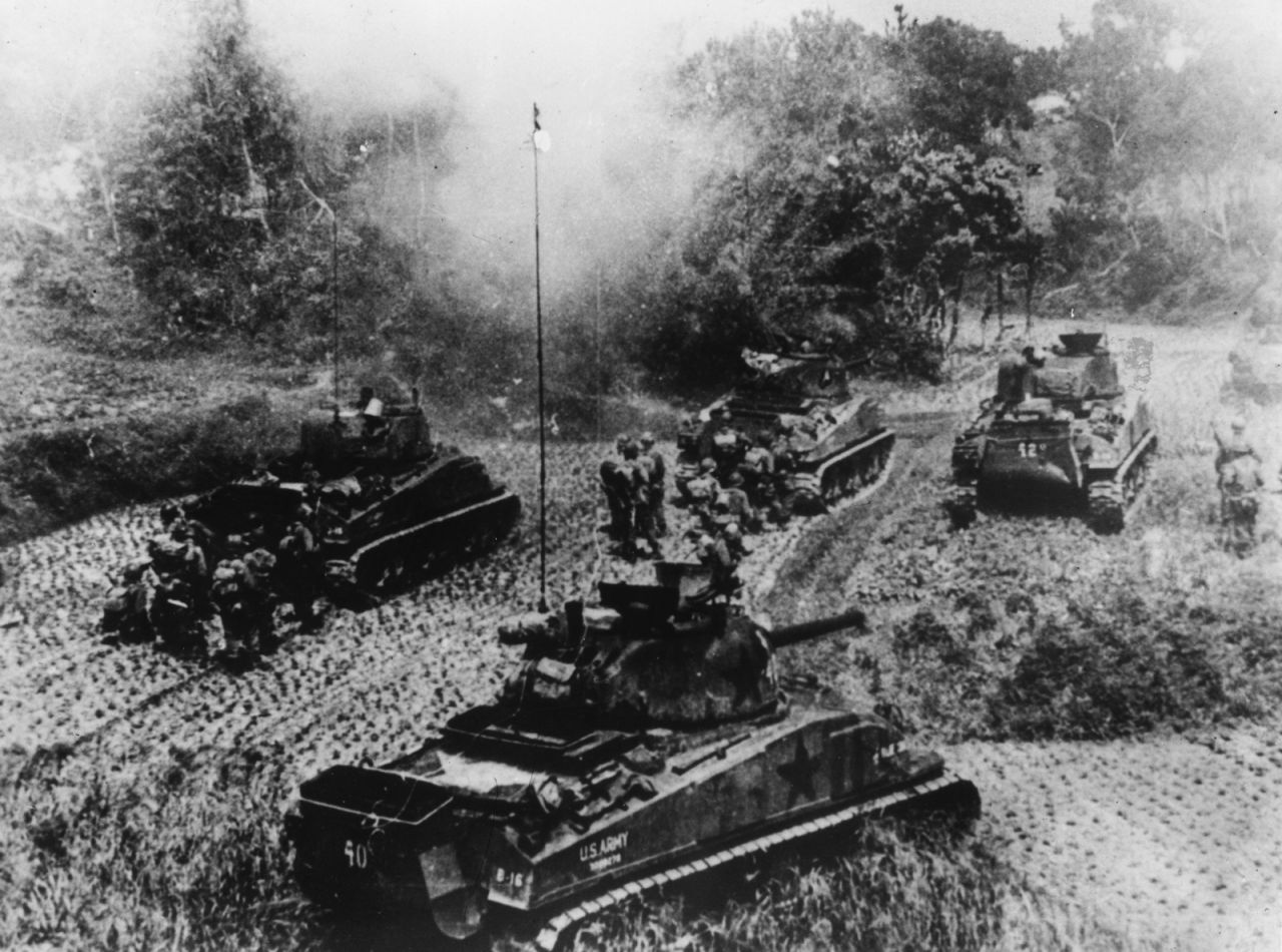 American tanks and infantrymen advance under Japanese attack during the Battle of Okinawa. 