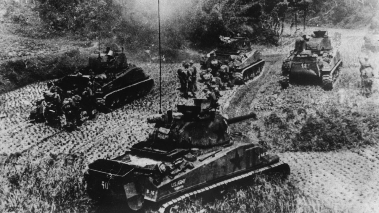 American tanks and infantrymen advance under Japanese attack during the Battle of Okinawa. 