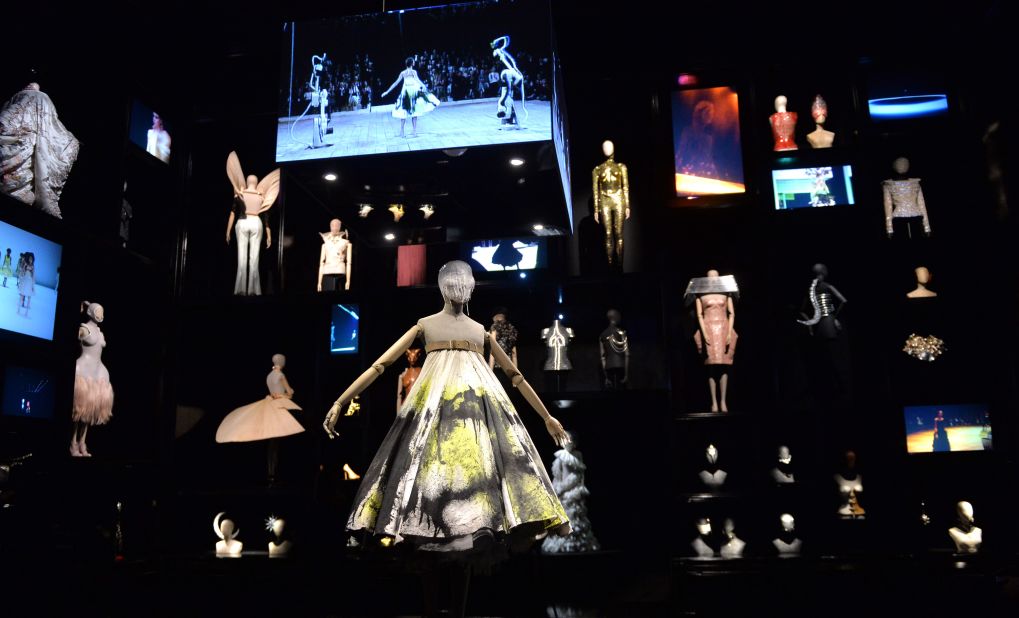 The high-ceiling "Cabinet of Curiosities" showcases his most creative pieces. The dress at the center of the room was spray-painted live on the runway by two robotic arms.
