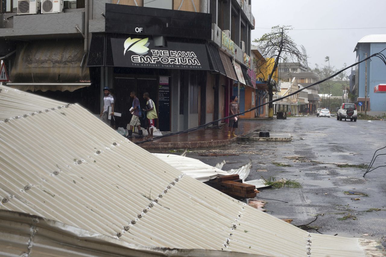 People walk past debris scattered on a street in Port Vila, Vanuatu, on Saturday, March 14. 