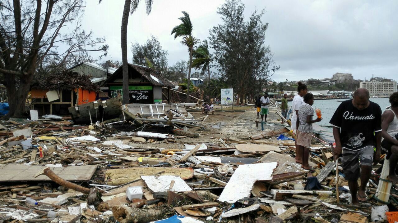 Locals walk past debris in Port Vila on March 15. 
