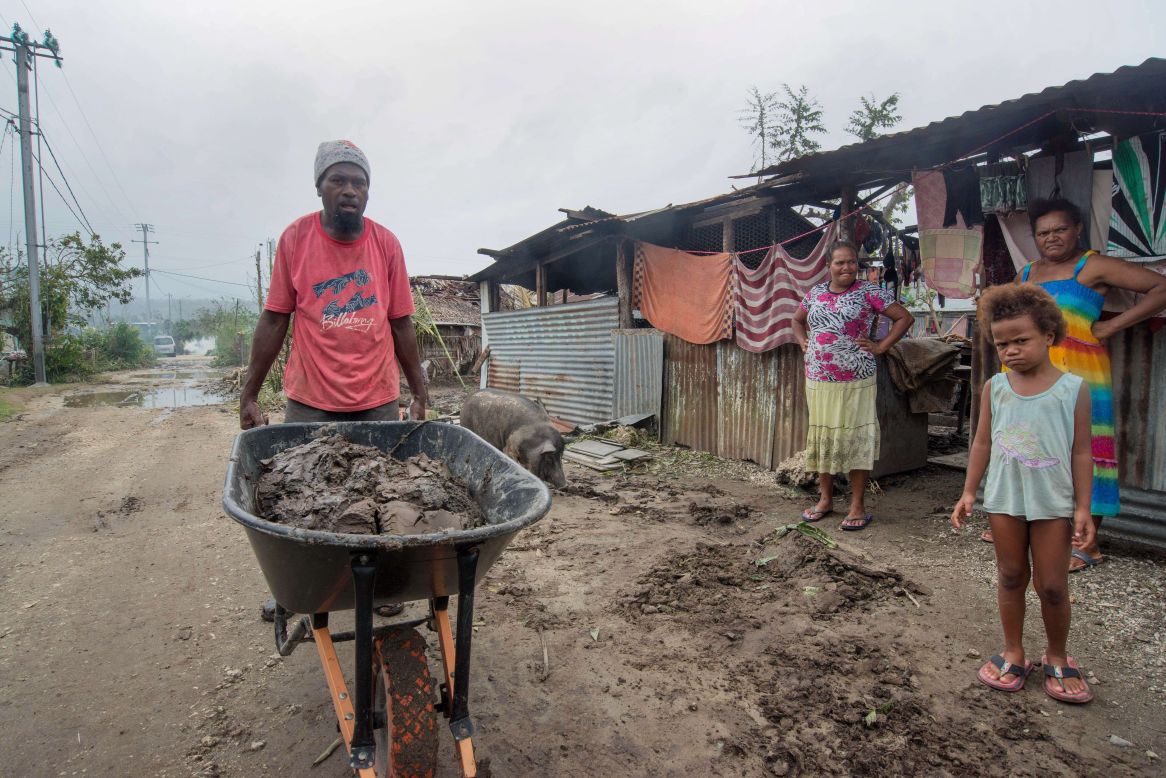 A resident clears mud and other debris outside homes near Port Vila  on March 15. 