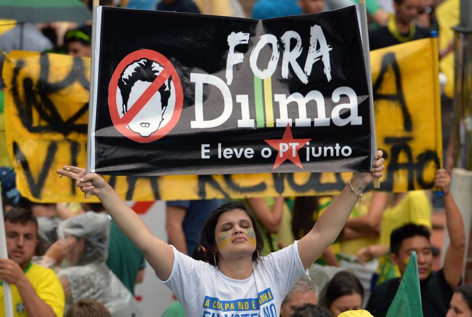A demonstrator holds a banner reading "Dilma out and take the Workers' Party with you." 