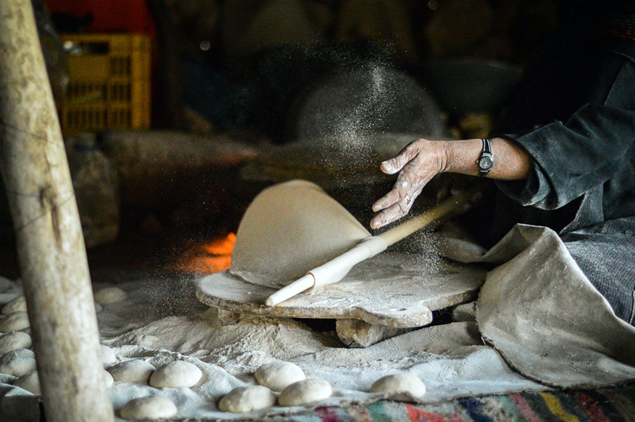 A Bakhtiari nomad makes fresh naan bread in her tent in the Zagros mountains of Iran. Countless little balls of dough are rolled out, flipped about, spun and thrown onto a sizzling metal plate that looks like an overturned wok to make instant bread