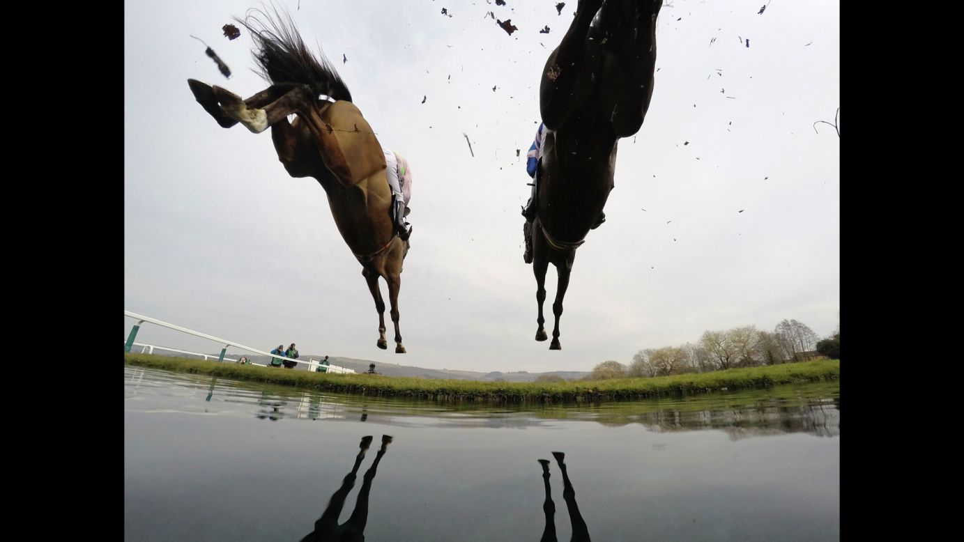 Horses clear water during a steeplechase race in Cheltenham, England, on Thursday, March 12.