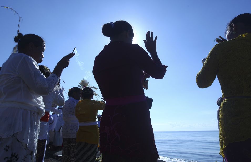 MARCH 17 - BALI, INDONESIA: Women offer prayers during a religious ceremony called Melasti. The ritual, in which the faithful carry a holy Hindu symbol to the sea to be purified, is performed ahead of the Hindu Day of Silence.