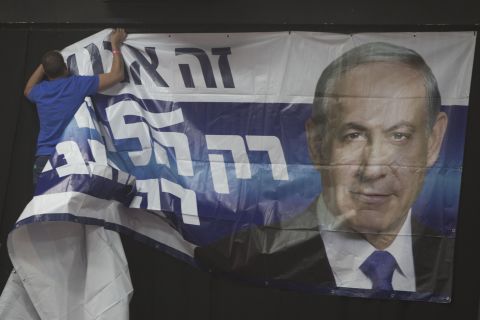 A man hangs a poster of Netanyahu at his election campaign headquarters in Tel Aviv on March 17.