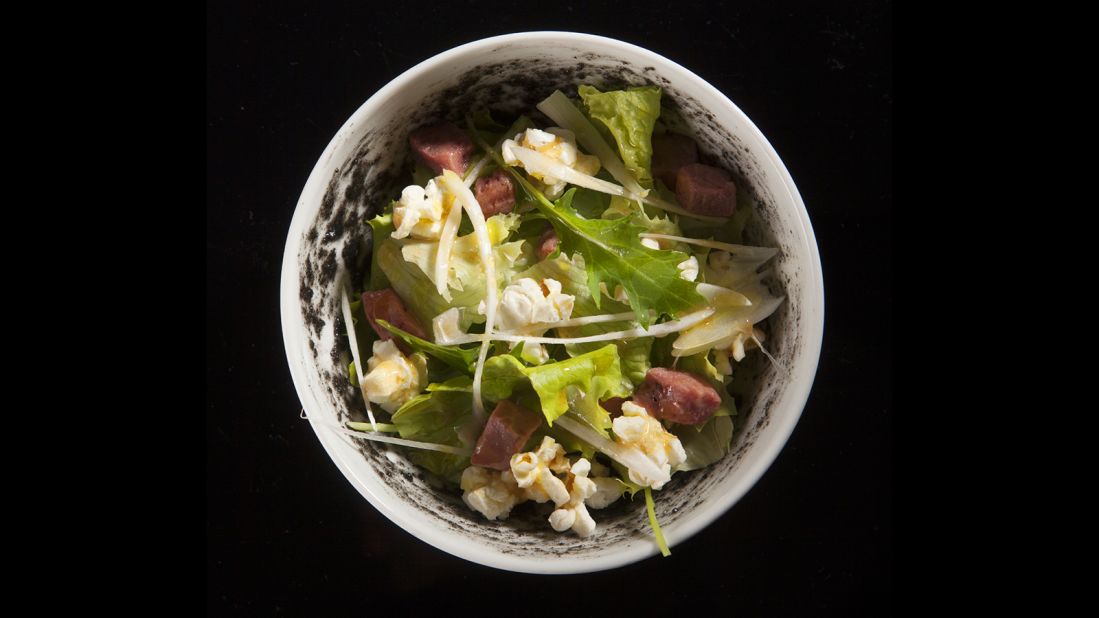 Butter lettuce salad and popcorn accompany cubes of T-bone steak, which dresses the tender leaves in beef juice and a slightly salty, buttery taste.