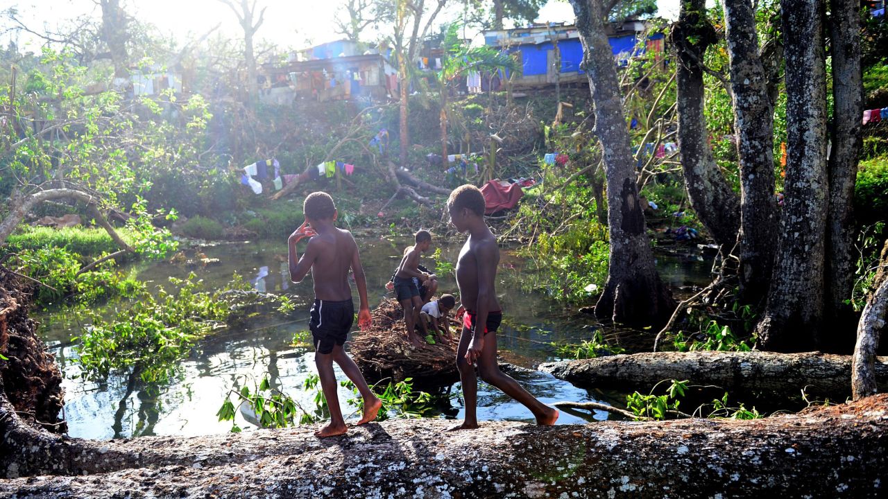 Children play on March 17 in water among fallen trees near Port Vila.