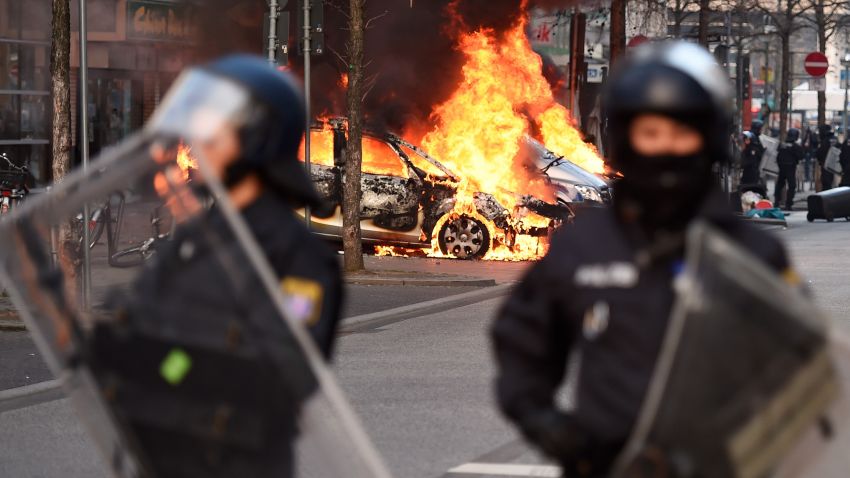 Riot Police form a cordon as a Police car burns on the opening day of the European Central Bank (ECB) in Frankfurt am Main, western Germany, on March 18, 2015.