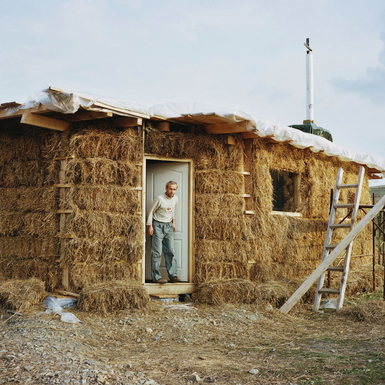 A man peers out from a house made of straw near the town of Zlatna in the Apuseni Mountains, Romania. <br /><br />Bruy visited five different countries -- France, Spain, Switzerland, Romania and Wales -- in carrying out his project.
