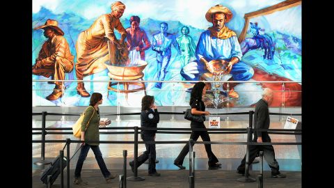 Travelers walk through security past a mural at Denver International Airport. Despite the criticisms, SPOT remains in place and has cost taxpayers well over $1 billion since its inception in 2007. The SPOT program should be terminated, Handeyside says. 
