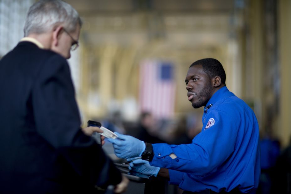 A TSA officer hands a passenger his identification at a security checkpoint at Ronald Reagan National Airport in Washington.  
