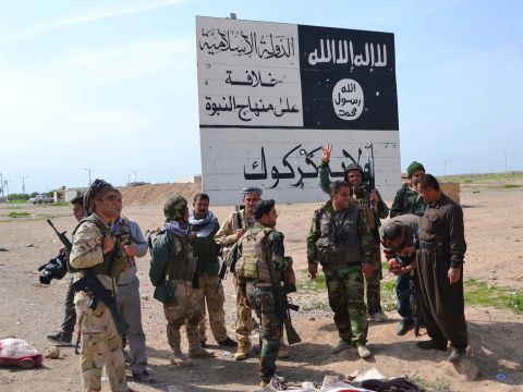 Peshmerga fighters stand next to an ISIS sign at the entrance to the northern Iraqi town of Hawija, south of Kirkuk in March 2015 after they reportedly re-took the area from ISIS jihadists.
