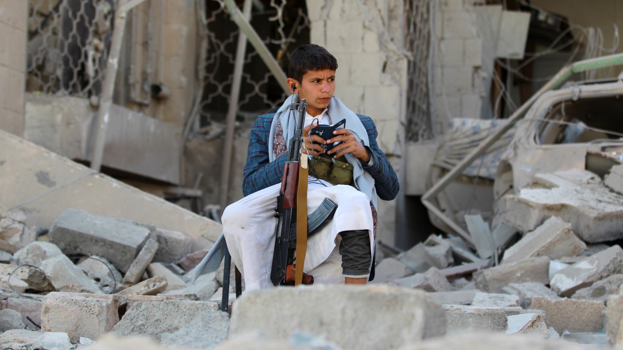 An armed Yemeni youth sits amid the rubble in December 2014, guarding the damaged house of the Iranian ambassador in the capital Sanaa.