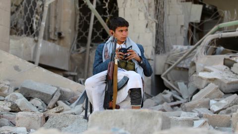 An armed Yemeni youth sits amid the rubble in December 2014, guarding the damaged house of the Iranian ambassador in the capital Sanaa. 