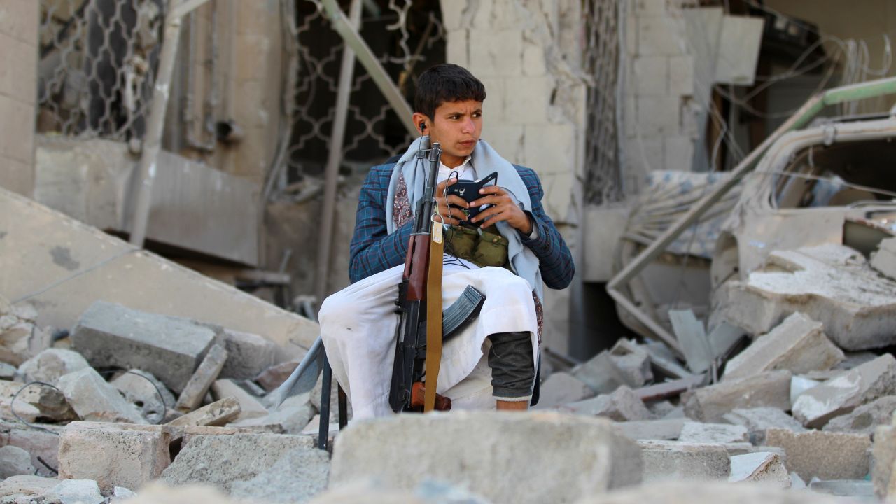 An armed Yemeni boy loyal to the Houthi movement sits amid rubble in Sanaa on December 5, 2014. 
