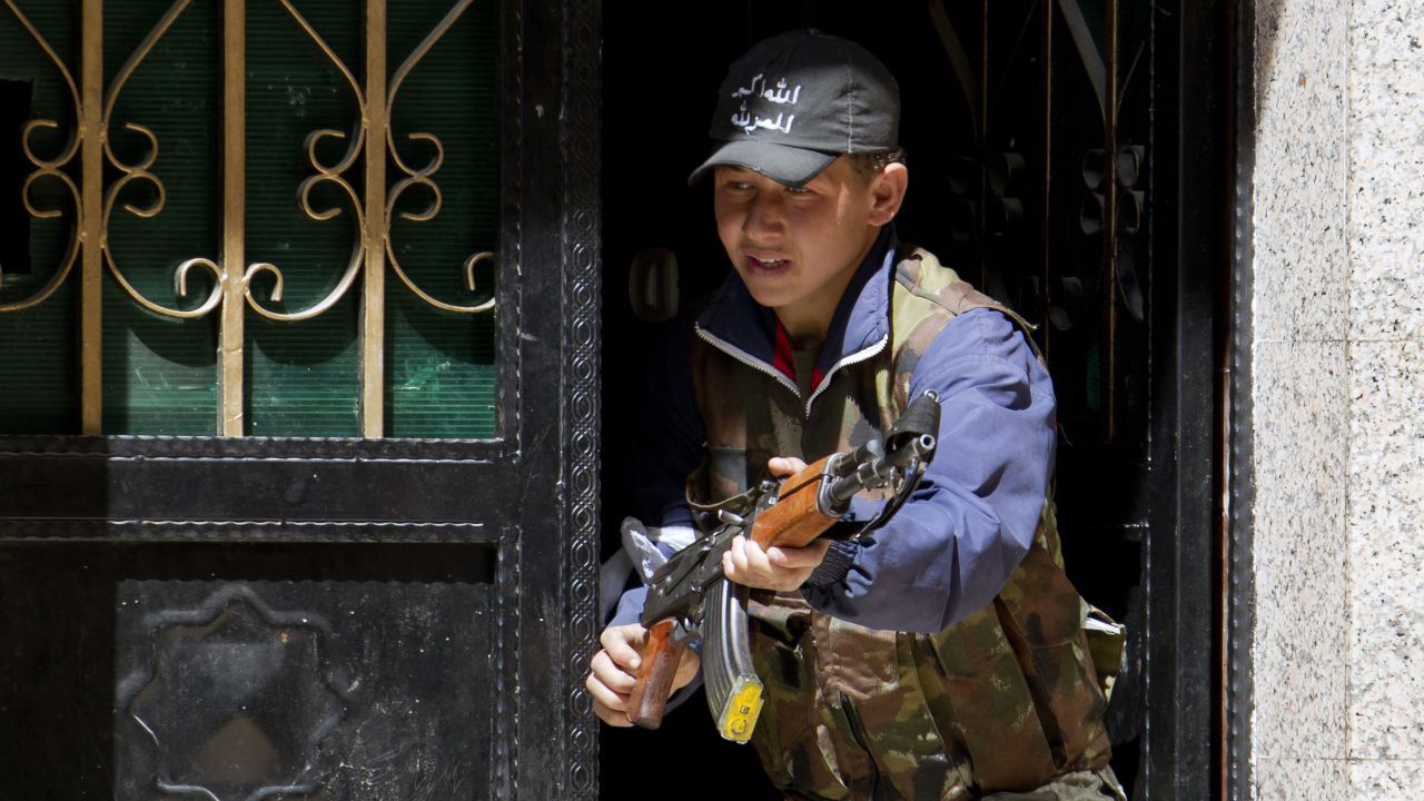 A young rebel fighter holds a weapon at the entrance of a house in the Syrian city of Aleppo in March 2013.