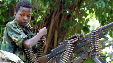 A Chadian child soldier stands in front of a machine gun at De Roux camp in Bangui, Central African Republic, in 2003.