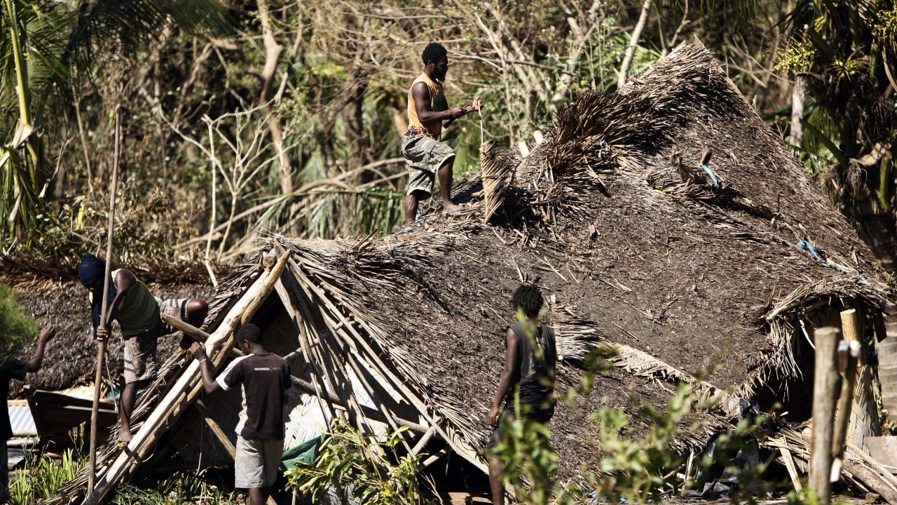 Young men take apart a damaged hut on March 19 on Tanna Island.