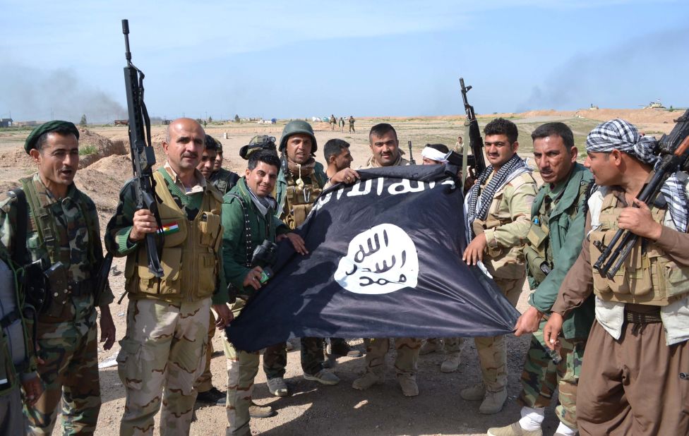 Iraqi Kurdish Peshmerga fighters pose for a photo with an ISIS flag in the village of Sultan Mari, west of the city of Kirkuk, in March 2015.