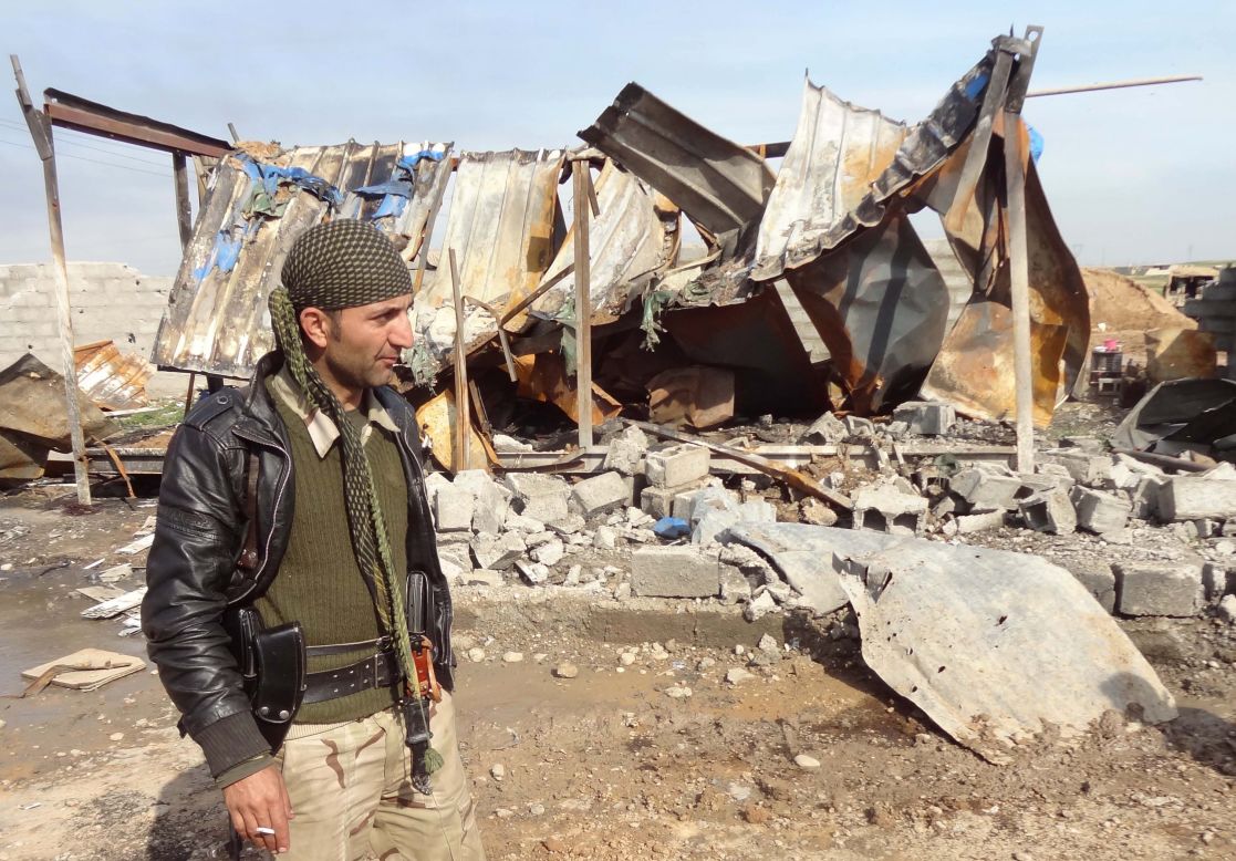 A member of the Iraqi Kurdish forces walks past a damaged building near Al-Assal village, 25 km west of Kirkuk, in February 2015.