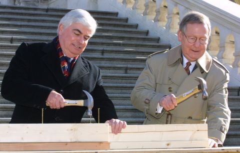 Sen. Christopher Dodd, D-Connecticut, and McConnell hammer the "first nails" into a piece of wood during a nail-driving ceremony in December 2000 on Capitol Hill. Both senators participated in the ceremony to signify the beginning of construction of the 2001 Inaugural platform on the West Front Terrace of the U.S. Capitol.