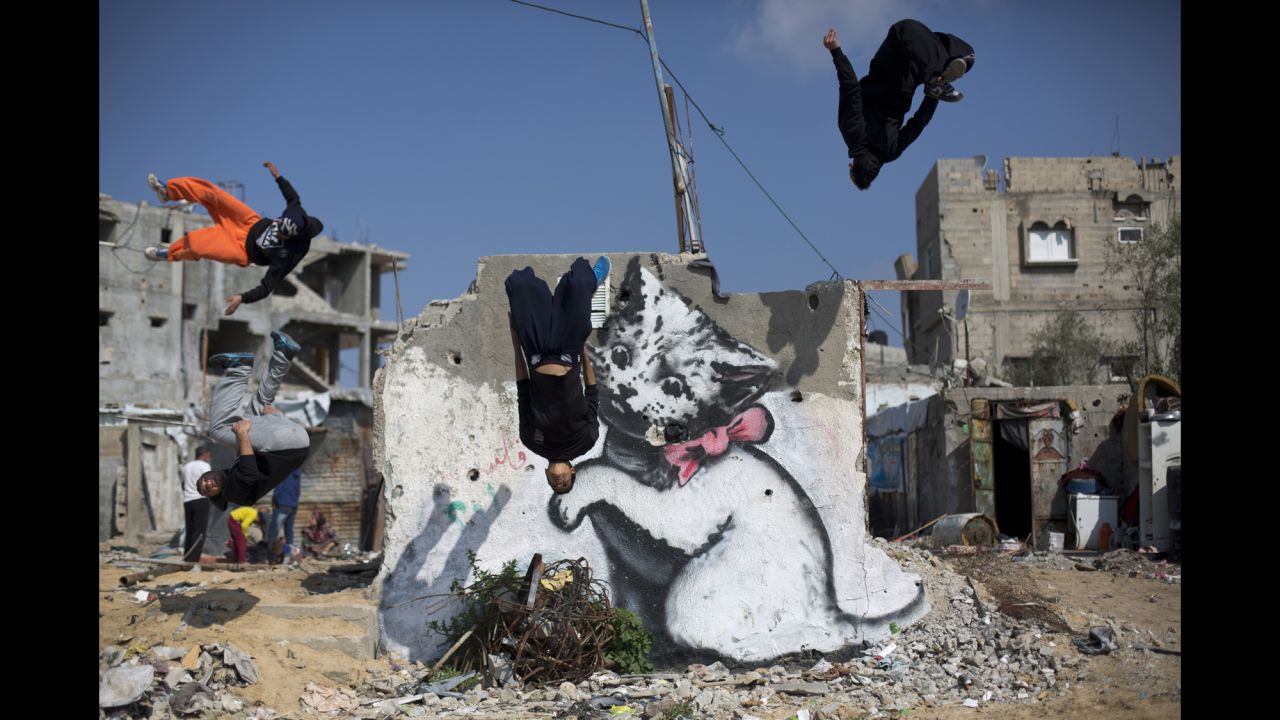 Palestinian youths in Beit Hanun, Gaza, practice their parkour skills Friday, March 13, on the remains of house that was destroyed last year during clashes between Hamas militants and Israel. The mural is said to have been painted by the British street artist Banksy.