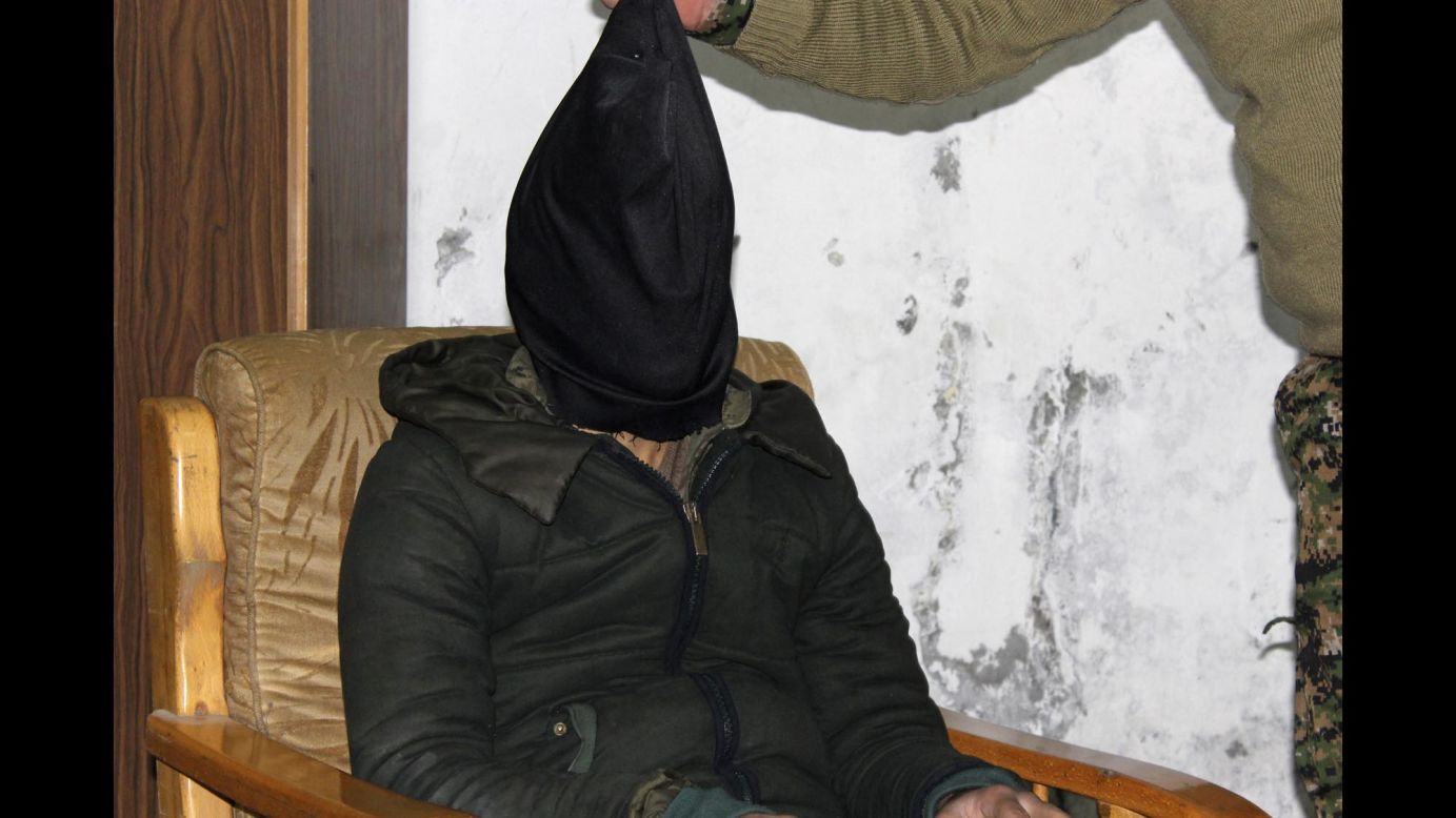 A man who Kurdish fighters said is an ISIS militant has a hood pulled from his head in an interrogation room in Al-Malikiyah, Syria, on Saturday, March 14.