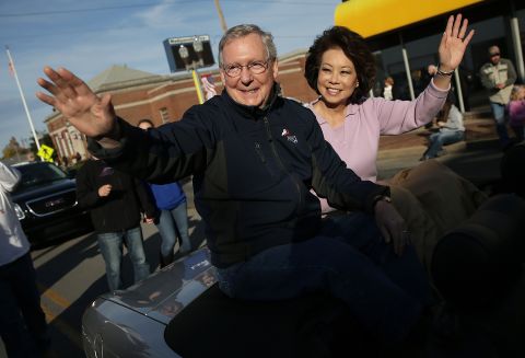 McConnell waves to a crowd while riding with his wife, Elaine Chao, in the Hopkins Country Veterans Day Parade in November 2014 in Madisonville, Kentucky. 