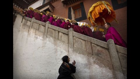 A woman prays as monks of the Yellow Hat order, carry a large thangka of Buddha after showing it to worshippers on March 3, 2015. 
