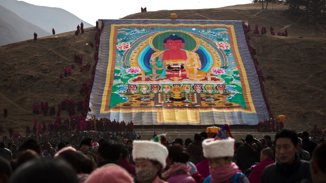 Monks unveil a large thangka -- a painting on silk or cotton -- showing Buddha, on a hillside near Labrang Monastery on March 3, 2015. 