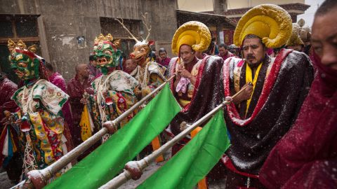 Tibetan Buddhist monks of the Gelug, or Yellow Hat order, some wearing masks, are covered in snow as they take part in a procession on March 4, 2015.