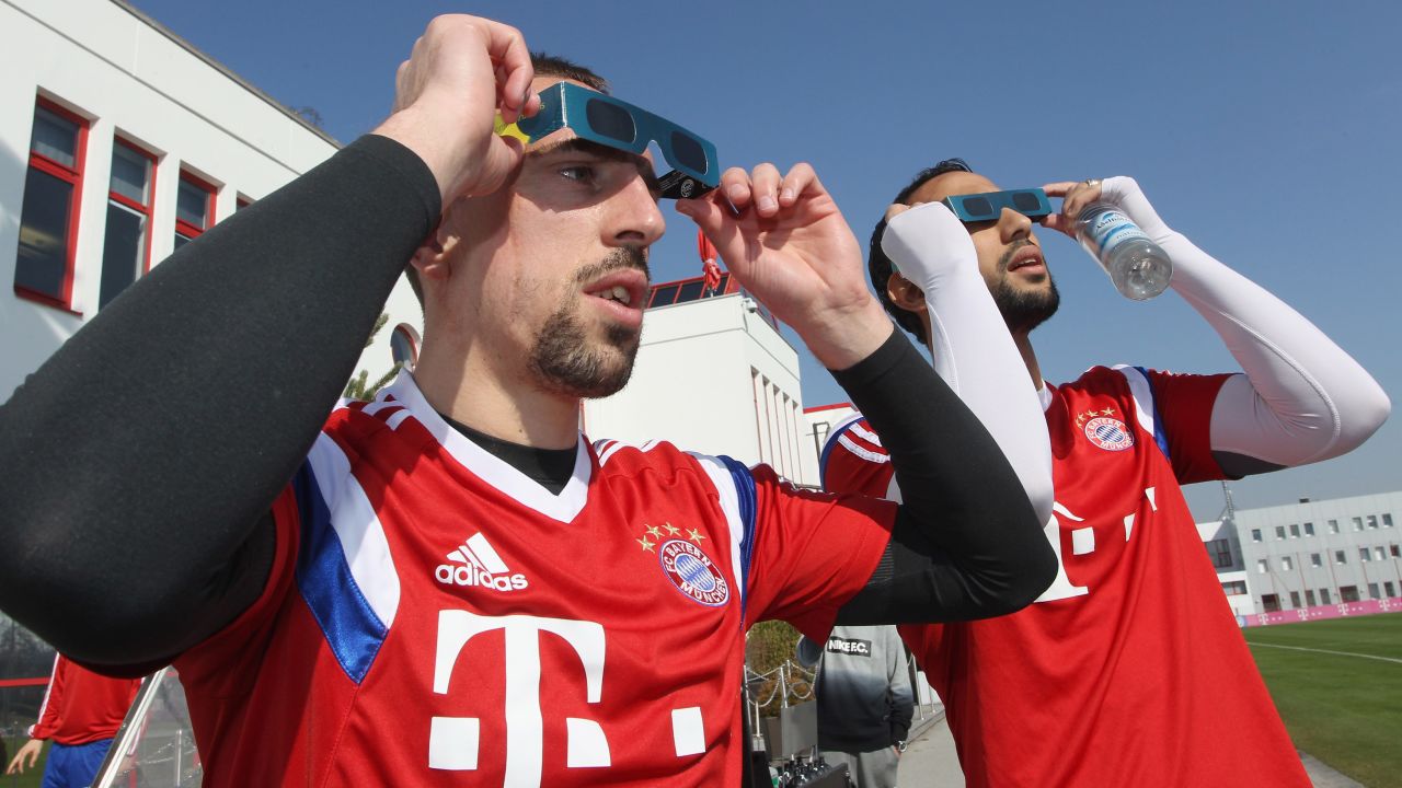 Franck Ribery, left, and Medhi Benatia of Bayern Muenchen soccer team watch the eclipse before a training session in Munich, Germany.