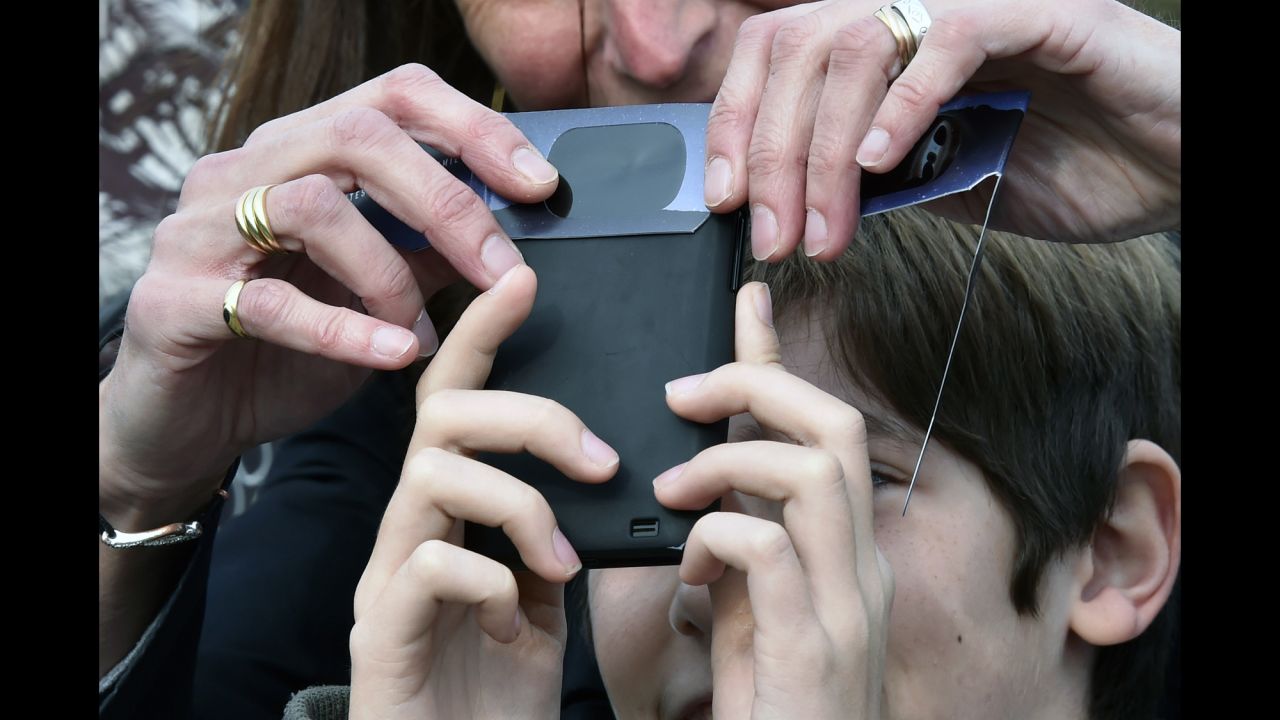 People try to take a picture of the eclipse with a smartphone in Toulouse, France.