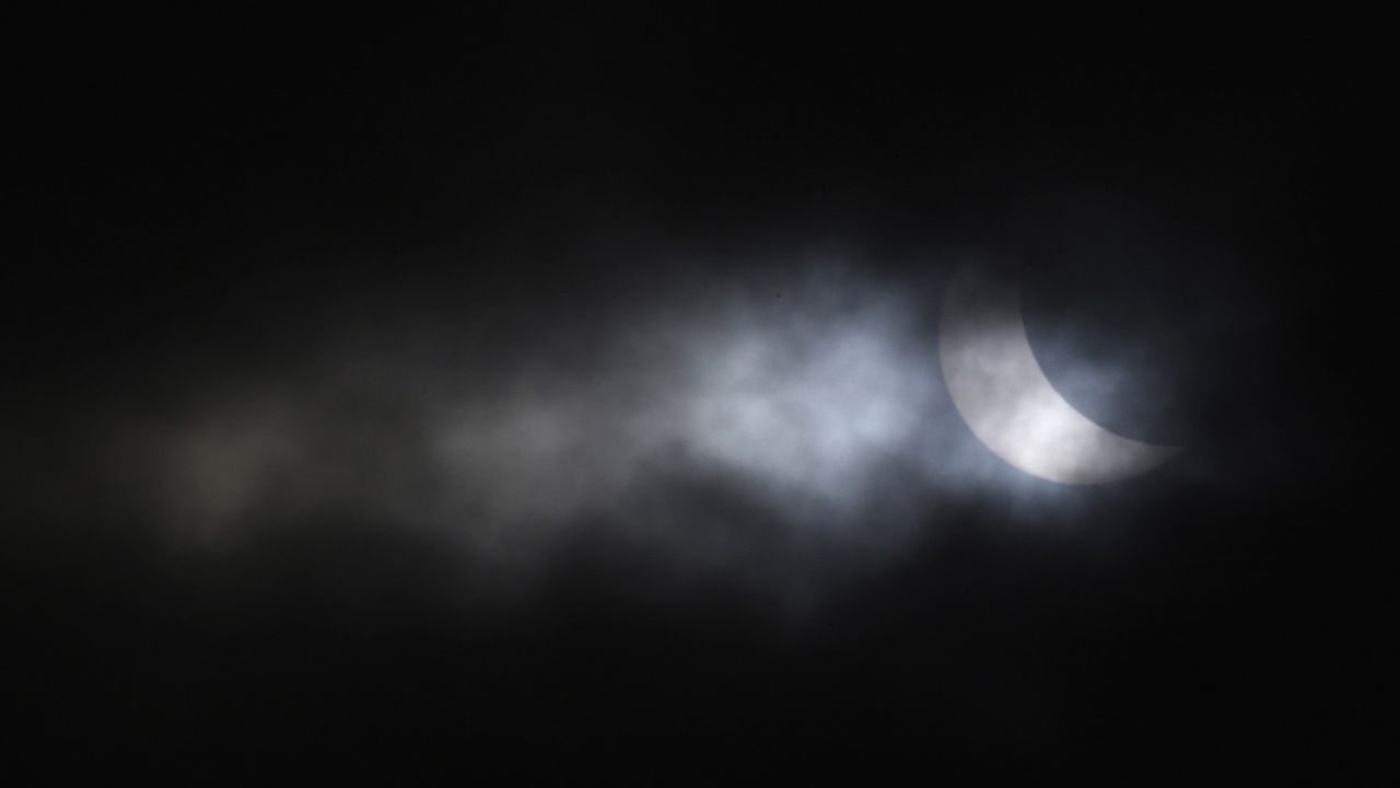 The eclipse is visible through a break in the clouds above Gateshead, England.