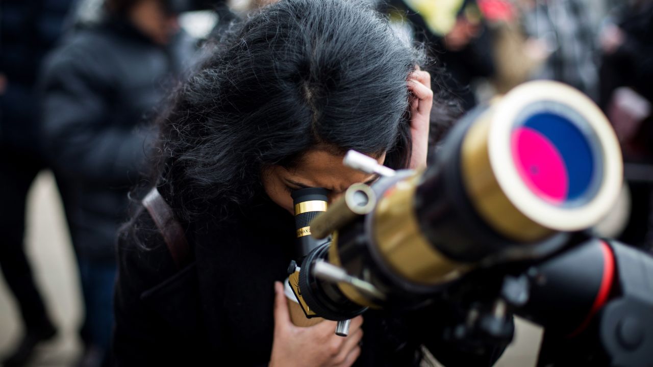 A woman looks through a telescope outside the Royal Observatory, Greenwich, in London.