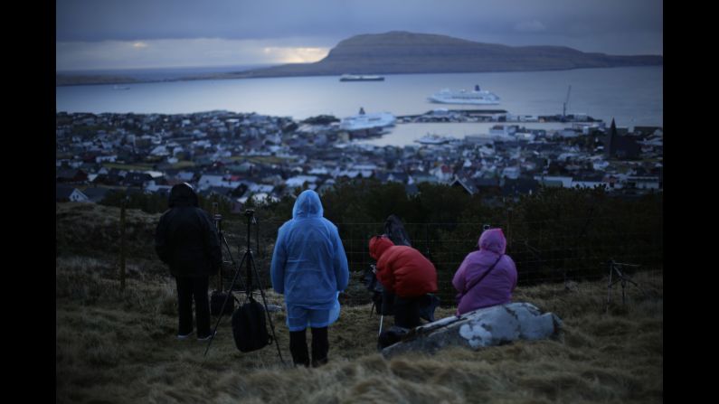 People wait for the start of the eclipse on a hill overlooking the sea and Torshavn, the capital of the Faroe Islands, between Scotland and Ireland.