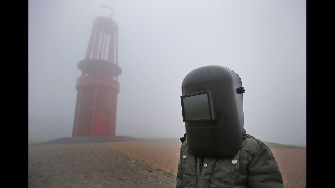 A boy wearing his father's welding mask gets disappointed after fog blocks the solar event from being viewed in Duisburg, Germany.