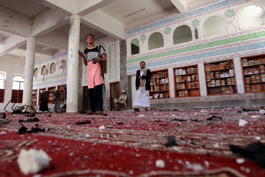Armed men inspect damage after an explosion at the Al Badr mosque in Sanaa on Friday, March 20.