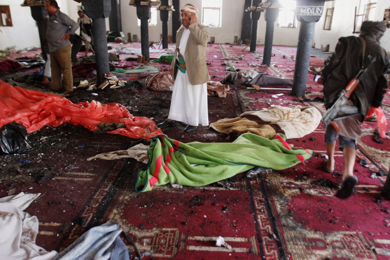 People stand amid bodies covered with blankets in a mosque after a suicide attack in Sanaa on March 20.