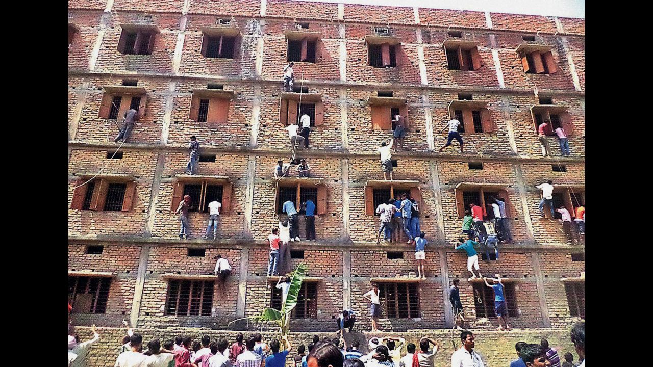 People climb the wall of a building in Hajipur, India, to help students during an examination inside on Wednesday, March 18.
