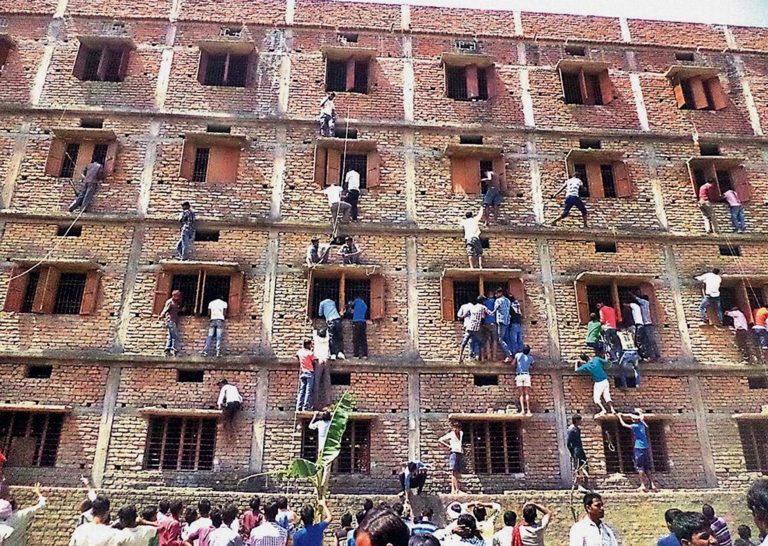 In this Wednesday, March 18, 2015 photo, parents climb the wall of a building to help students appearing in an examination in Hajipur, in the eastern Indian state of Bihar. 